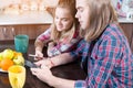 An attractive young Caucasian couple in the kitchen at the dinner table drinks tea and uses their smartphones. Royalty Free Stock Photo