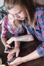 An attractive young Caucasian couple in the kitchen at the dinner table drinks tea and uses their smartphones. Royalty Free Stock Photo