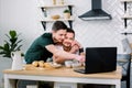 Attractive young Caucasian gay couple, homosexual couple, in kitchen, embracing and having breakfast at the dinner table Royalty Free Stock Photo