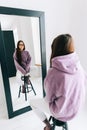 Attractive young caucasian woman in eyeglasses looking at mirror in living room at home