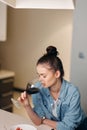 The Attractive Young Caucasian Woman, Holding a Wine Glass, Sitting Alone in her Elegant Kitchen, Enjoying a Glass of Royalty Free Stock Photo