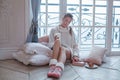 Attractive young cheerful winter woman sitting on wooden floor and drinking tea indoor Royalty Free Stock Photo