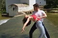 Attractive young couple dancing sensual bachata on a stone floor, in an outdoor park, next to a river. Latin dance concept, Royalty Free Stock Photo