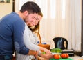 Attractive young couple embracing happily while chopping vegetables together, cooking with love concept Royalty Free Stock Photo