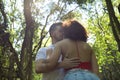 Attractive young couple in love, looking into each other`s eyes, close faces about to kiss, in an outdoor park, surrounded by