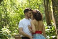 Attractive young couple in love, looking into each other`s eyes, close faces about to kiss, in an outdoor park, surrounded by