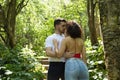 Attractive young couple in love, looking into each other`s eyes, close faces about to kiss, in an outdoor park, surrounded by