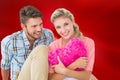 Attractive young couple sitting holding heart cushion Royalty Free Stock Photo