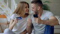 Attractive young couple with smartphone and credit card shopping on the internet sit on bed at home Royalty Free Stock Photo