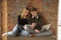 Attractive young couple using devices together, tablet, laptop, smartphone, headphones wireless. Gadgets and Royalty Free Stock Photo