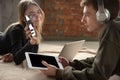 Attractive young couple using devices together, tablet, laptop, smartphone, headphones wireless. Gadgets and Royalty Free Stock Photo