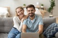 Attractive young couple using pc sitting on couch at home Royalty Free Stock Photo