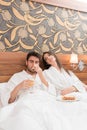 Attractive young couple in white robes, enjoying food and drink