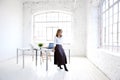 Attractive young creative woman standing at office desk and looking thoughtfully Royalty Free Stock Photo