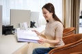 Attractive young Caucasian woman browsing a catalog of services while sitting in a comfortable chair at a desk at the reception