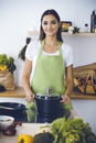 An attractive young dark-haired woman preparing soup by new keto recipe while standing and smiling in the kitchen Royalty Free Stock Photo