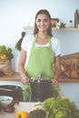 An attractive young dark-haired woman preparing soup by new keto recipe while standing and smiling in the kitchen Royalty Free Stock Photo