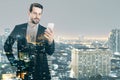 Attractive young european businessman using cellphone while standing on night city background. Success, technology, communication Royalty Free Stock Photo