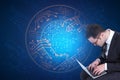 Attractive young european businessman using laptop with abstract glowing digital circuit sphere on blue background. Hardware, Royalty Free Stock Photo