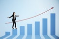 Attractive european businesswoman balancing on blue business chart and red arrow. Finance, growth and success concept