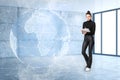 Attractive young european businesswoman with glowing futuristic blue globe hologram writing in blurry empty white office Royalty Free Stock Photo