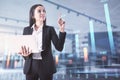 Attractive young european businesswoman with laptop and abstract forex chart standing on blurry background with mockup place. Royalty Free Stock Photo