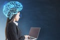 Attractive young european businesswoman with laptop and glowing digital brain hologram standing on blurry chalkboard wall Royalty Free Stock Photo