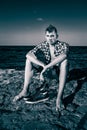 Attractive young fashion man on rock near the sea water in Royalty Free Stock Photo