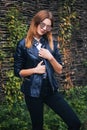 Attractive, young, fashionably dressed woman on the background of a wicker fence made of branches