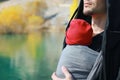 Attractive young father with her infant baby in sling outdoor. Man is carrying her child and travel in autumn mountain lake.