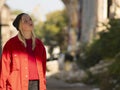 Attractive young female blonde teenager in a red jacket standing on the street Royalty Free Stock Photo