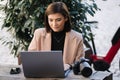 Attractive young female freelancer working on laptop on terrace in cafe. Woman photographer retouch photos on open air Royalty Free Stock Photo