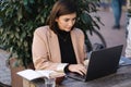 Attractive young female freelancer working on laptop on terrace in cafe. Woman photographer retouch photos on open air Royalty Free Stock Photo