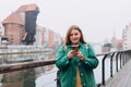 Attractive young female tourist is exploring new city. Gdansk old town and famous Zuraw crane, A happy beautiful 30s Royalty Free Stock Photo