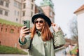 Attractive young female tourist is exploring new city. Redhead girl holding a smartphone in Krakow. Traveling. Happy Royalty Free Stock Photo