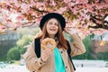 Attractive young female tourist is holding prezel, traditional polish bagel near Wawel castle, in Krakow. Traveling