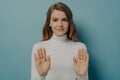 Attractive young focused woman showing stop gesture, saying no, isolated over blue studio background Royalty Free Stock Photo