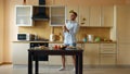 Attractive young funny man dancing and singing with ladle while cooking in the kitchen at home Royalty Free Stock Photo