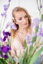 Attractive young girl with blond curly hair and beautiful make-up in a delicate blond chiffon blouse with blue irises