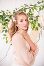 Attractive young girl with blond curly hair and beautiful make-up in a chiffon blouse with white orchids