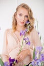 Attractive young girl with blond curly hair and beautiful make-up in a delicate blond chiffon blouse with blue irises