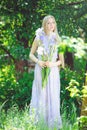 Attractive young girl with blonde hair and natural make-up smelling blue purple iris flowers on a background outdoors, tender Royalty Free Stock Photo