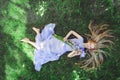 Attractive young girl with blonde hair and natural make-up smelling blue purple iris flowers lying on grass outdoors, tendern Royalty Free Stock Photo