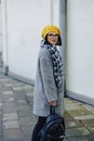 Attractive young girl in glasses in coat and yellow Beret freestyle walking