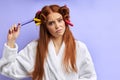 Attractive young girl in hair curlers isolated in purple background Royalty Free Stock Photo