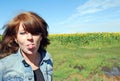 The attractive young girl, happy puts out the tongue against the background of the field of sunflowers Royalty Free Stock Photo