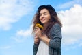 Attractive, young girl in jeans and a black hat holding a blooming dandelions.