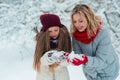 Attractive young girl with mother in winter time outdoor blowing snow Royalty Free Stock Photo