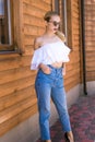 Attractive young girl with a perfect figure and blond hair in trendy jeans and a white top with ruffles and sunglasses Royalty Free Stock Photo