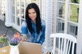 Attractive young girl sits in a cafe, reads sms on her smartphone and smiles, uses laptop for work. The concept of Royalty Free Stock Photo